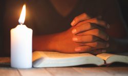 Religious concepts, The young man prayed on the Bible in the room and lit the candles to illuminate.