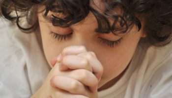 A boys prays earnestly to his creator in heaven