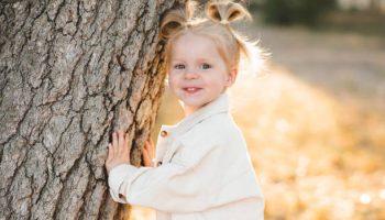 Laughing blonde child girl 4-5 year old having fun over nature background outdoor. Autumn season. Childhood.