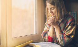 Beautiful woman praying having the Bible opened in front of he